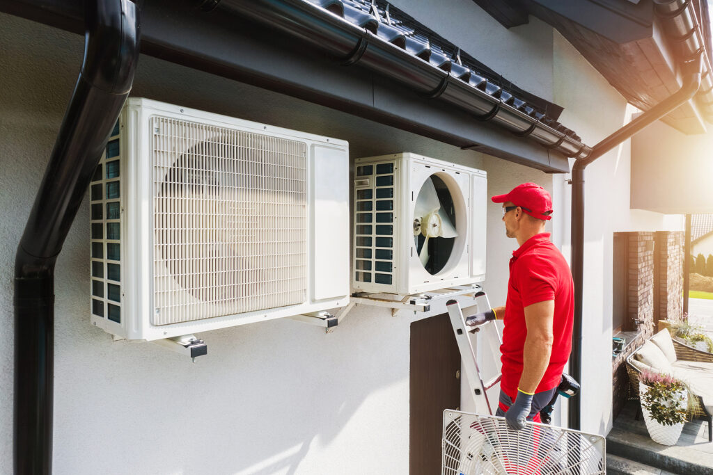 Caucasian Professional HVAC Technician Performing Air Condition and Heat Pump Units Maintenance. Residential Heating and Cooling Theme.